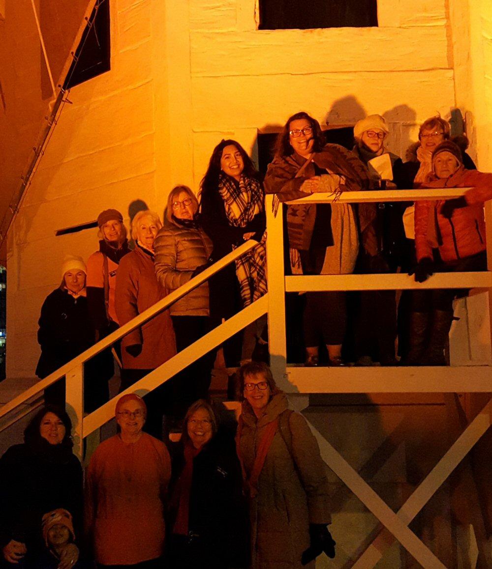 CFUW Nanaimo and VUFA representatives stand in front of Bastion which is lighted organge