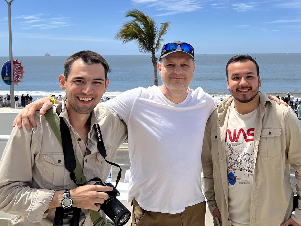 Jonathan, Greg and Robert smile while standing on the beach.