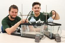 Kyle Wickland and Oscar Thoms have two glass tanks in front of them with thermometers and temperature gauges.