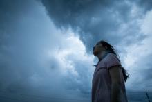 A woman stares up at a gray sky