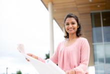 Woman holding blueprints smiling at the camera