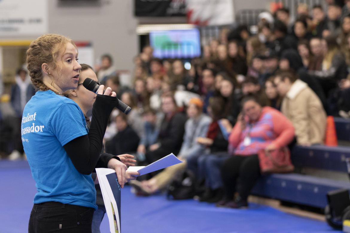 A student speaks into a microphone in front of a crowd