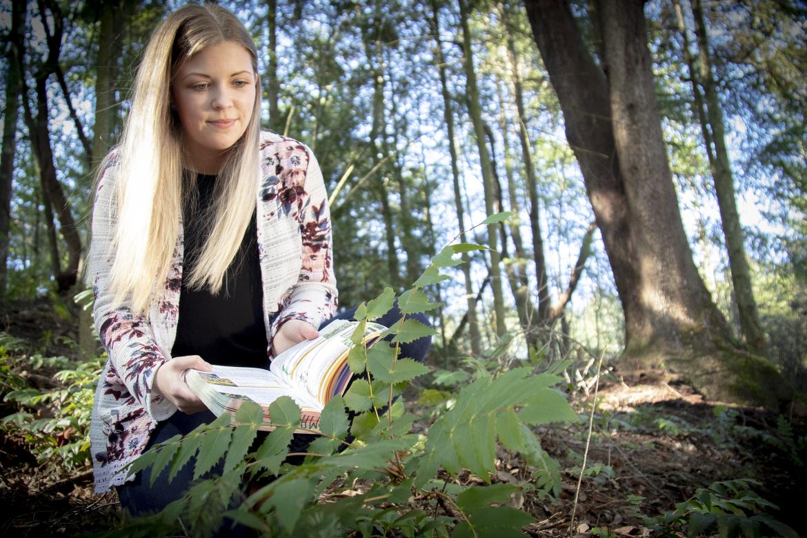 Mandy Hobkirk uses an identification book while examining plants at VIU's Nanaimo Campus.