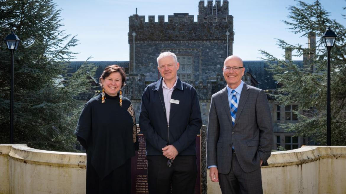 Three people standing in front of Royal Roads University