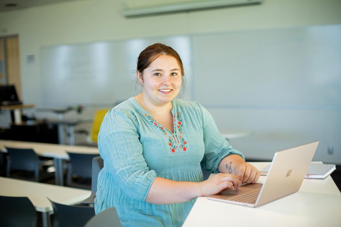 Sarah types on a laptop in a classroom