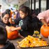 A group of kids carve pumpkins together