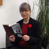 Katharina wears a poppy and holds a copy of her translation of All Quiet on the Western Front