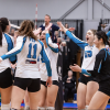 A group of VIU Mariners women's volleyball teammates celebrate in a circle on the volleyball court